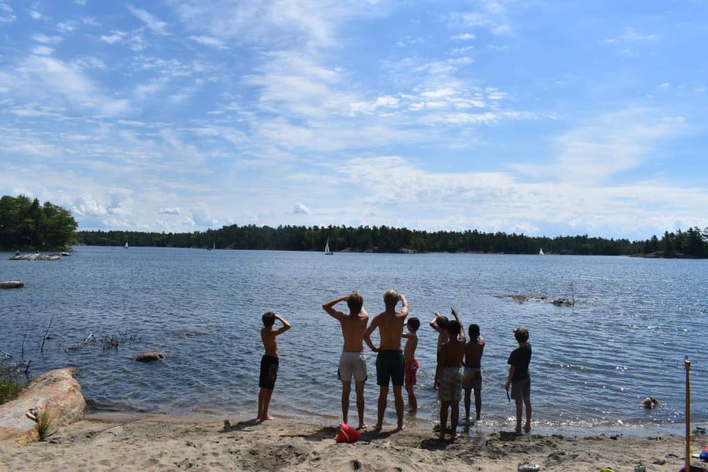 Group of boys looking out to lake from beach
